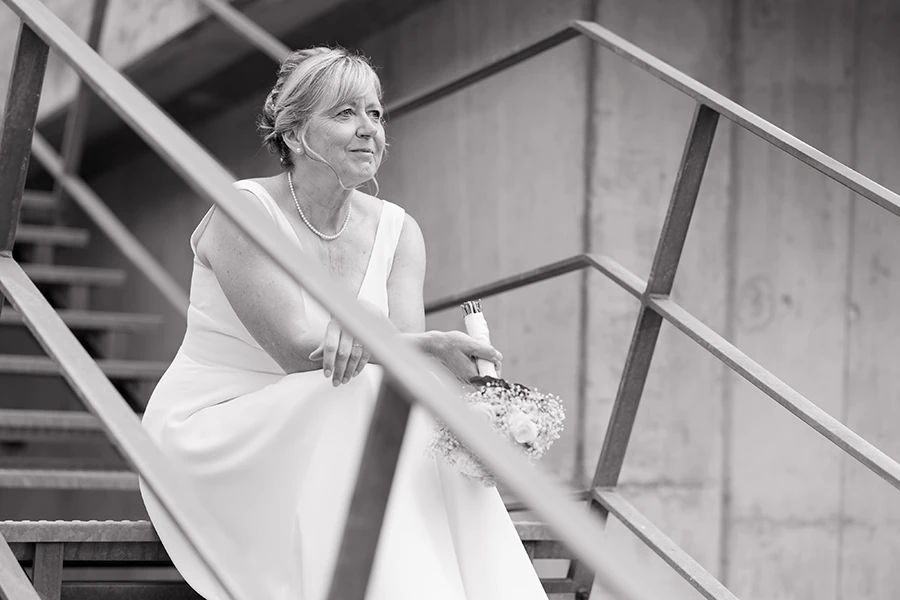 Schwarz-weiß Aufnahme der Braut, die auf einer Treppe sitzt.